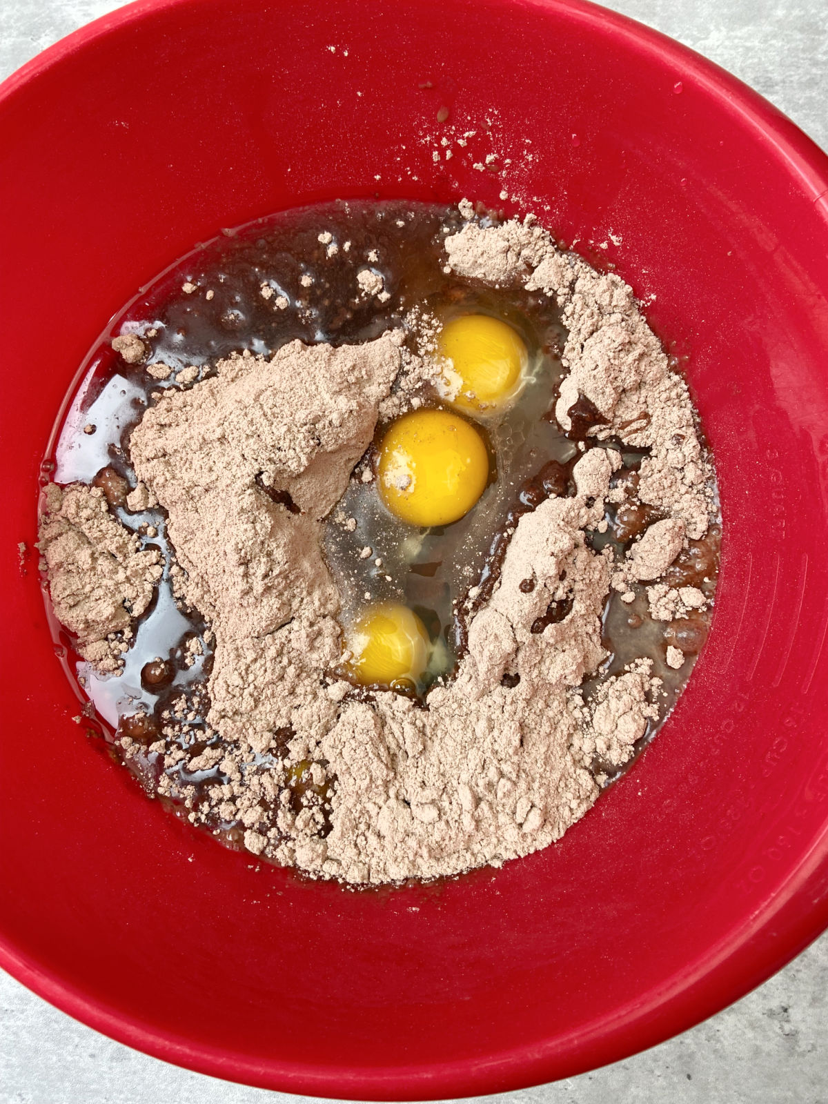 Eggs in a red bowl with brownie mix. 