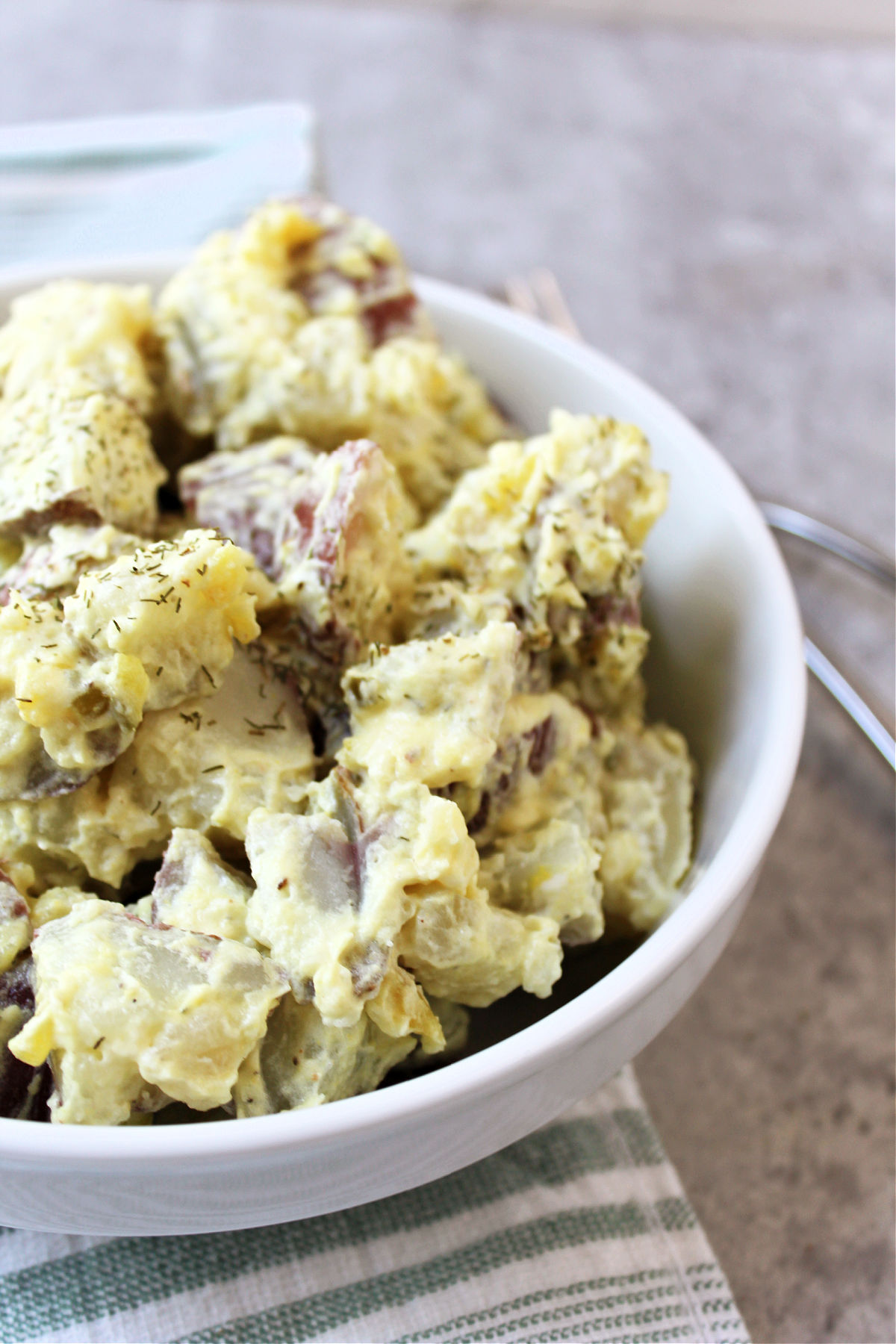 potato salad in a white bowl with a towel.