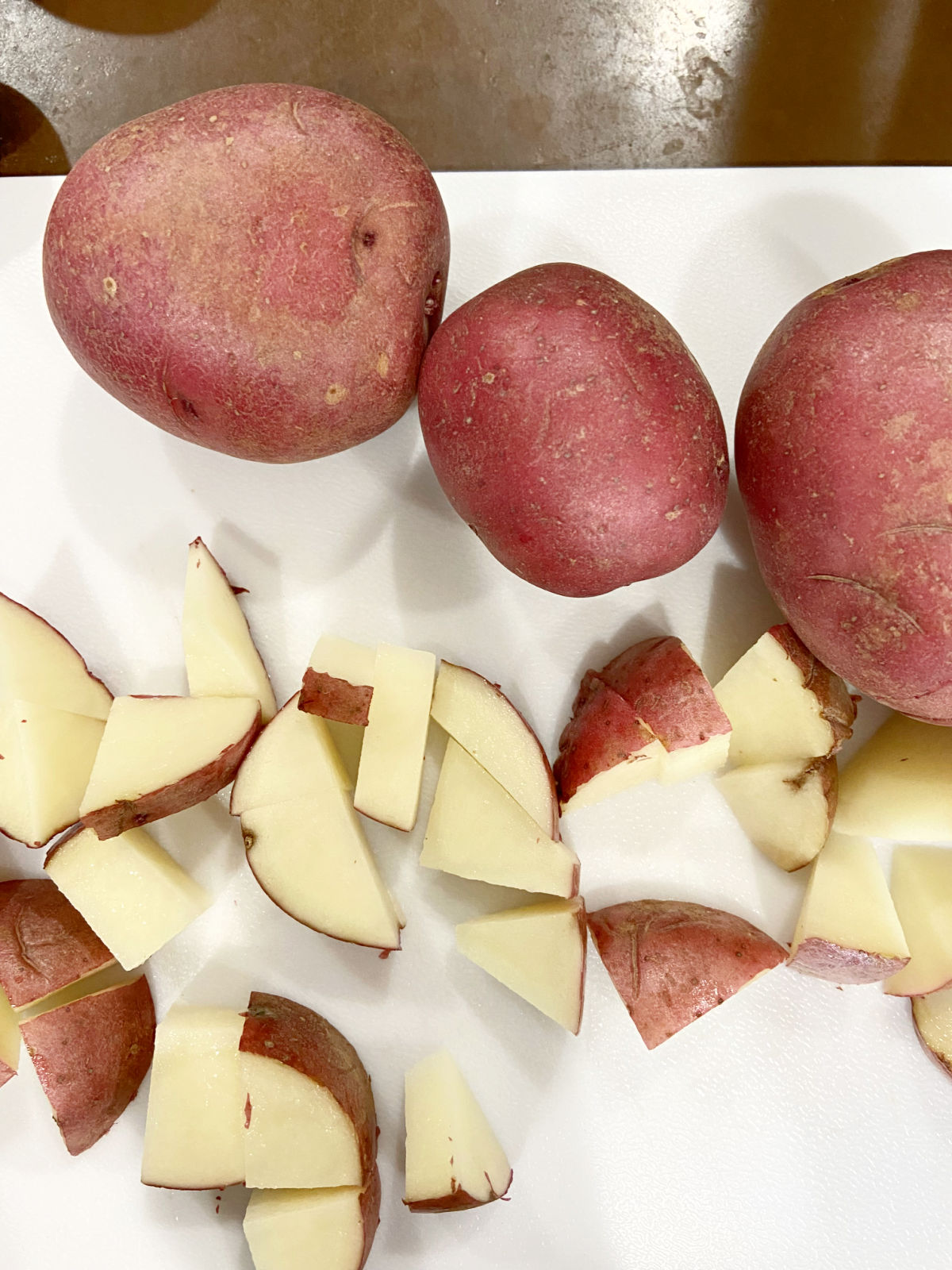 red potatoes cut up on cutting board. 