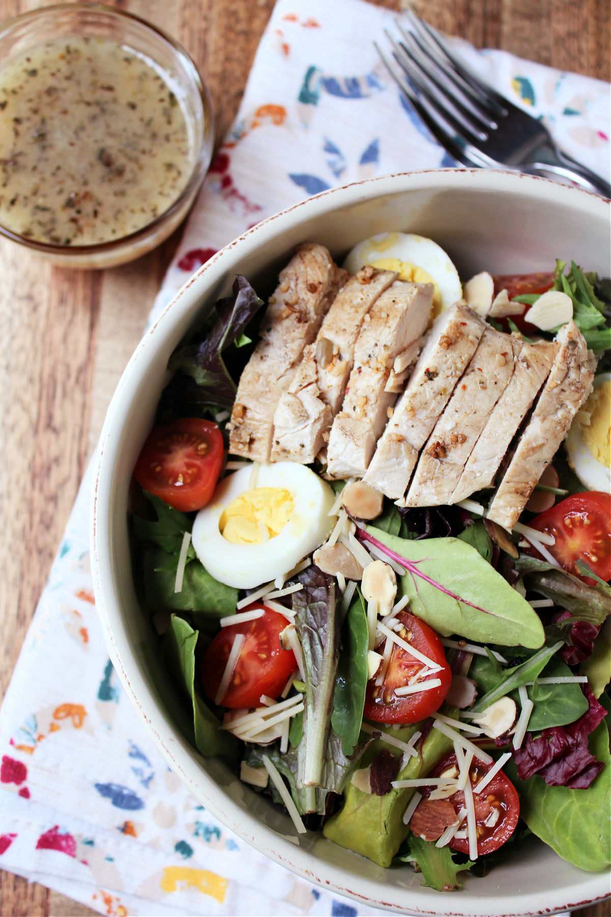 grilled chicken salad in a white bowl with a bowl of salad dressing. 