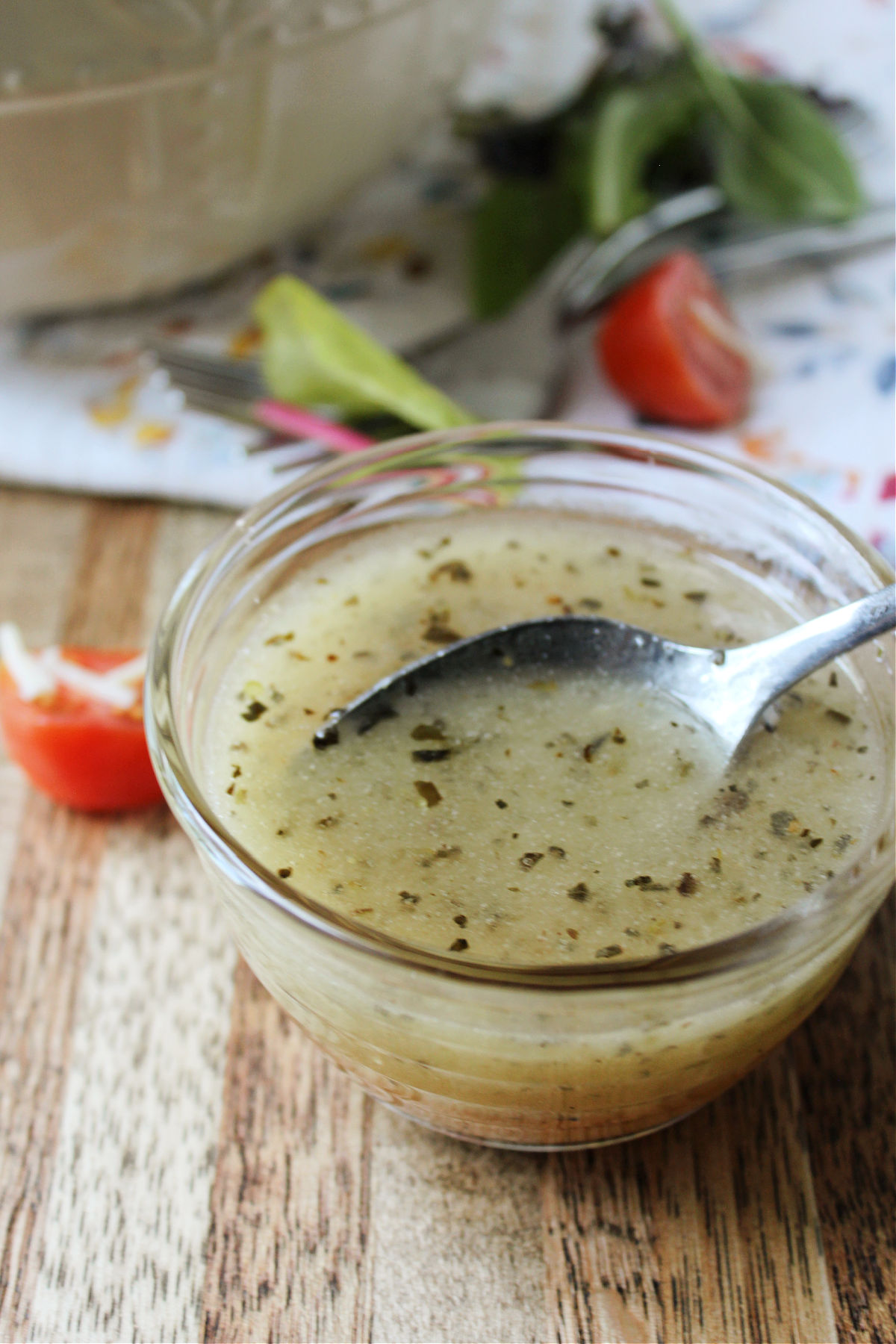 Italian dressing in a clear bowl with a spoon. 