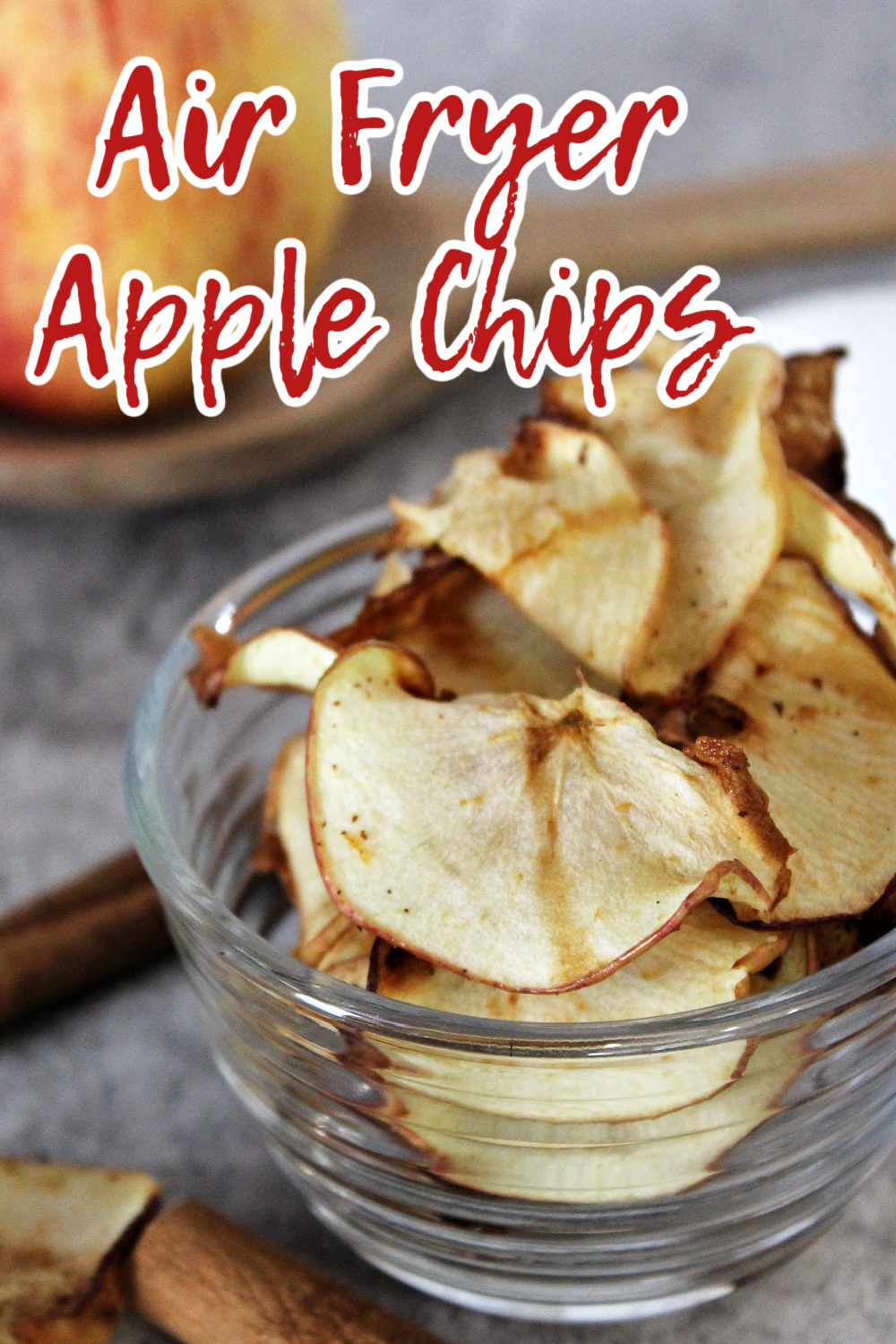 Air fryer apple chips with an apple behind. 