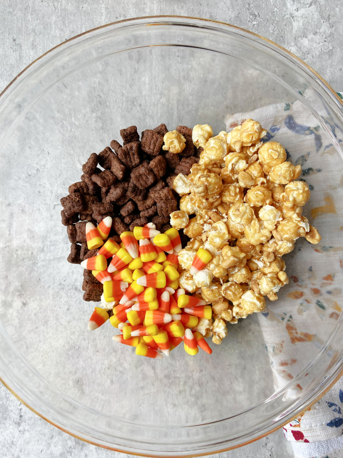 popcorn, candy corn and cereal in a clear bowl. 