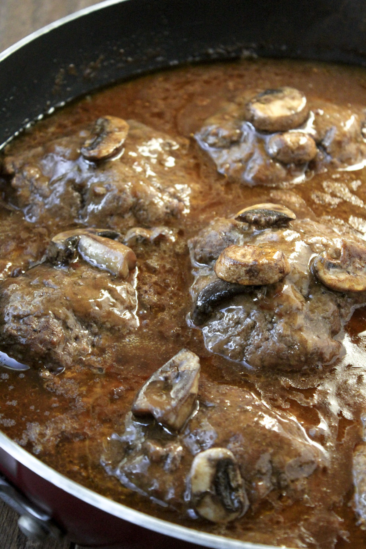 Salisbury Steak in a pan with mushrooms. 
