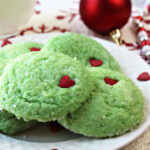 Easy Grinch Cookies on a white plate with Christmas decor behind.