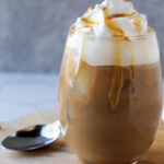 Iced caramel latte with whipping cream with caramel drizzle on top.