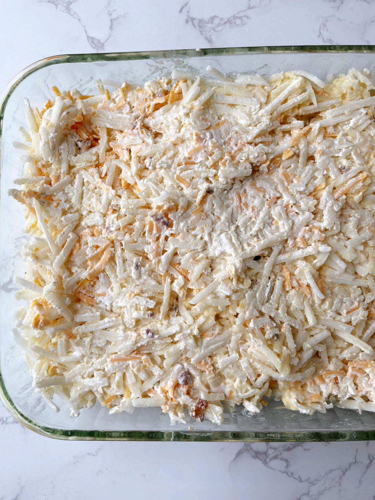 Shredded potatoes in a clear baking dish. 