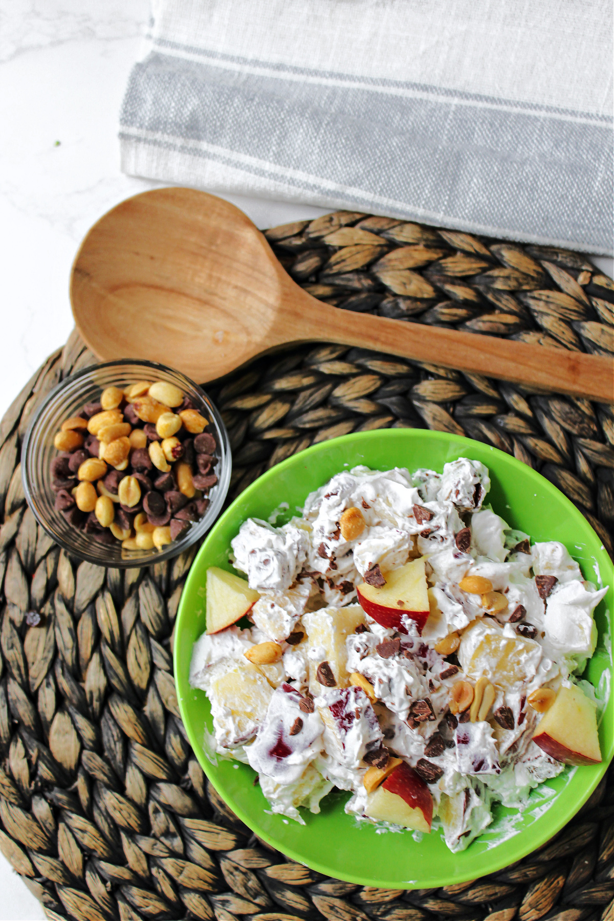 Snickers Salad in a green bowl with peanuts to the side. 
