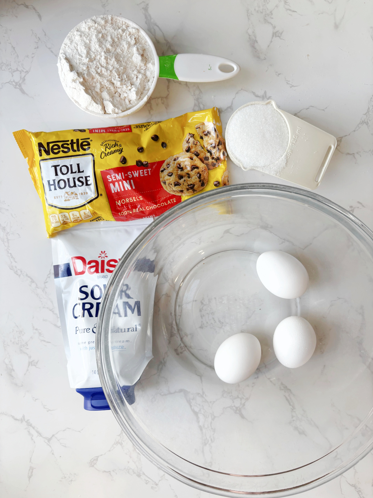 eggs, sour cream and flour by a bowl. 