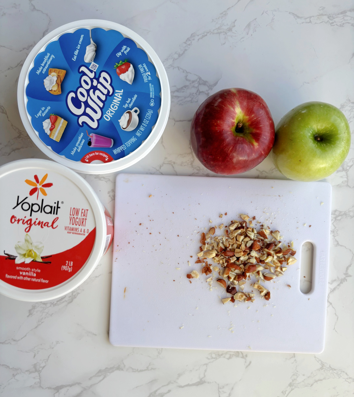 yogurt, apples and nuts on a cutting board. 