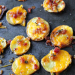 potato slices on a pan with cheese and bacon.