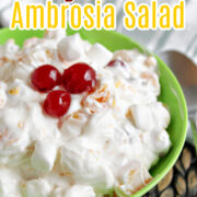 Easy Ambrosia Salad in a green bowl with cherries on top.