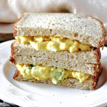 egg salad on a white plate with a towel behind.