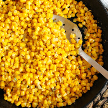 fried corn in a frying pan with a spoon.