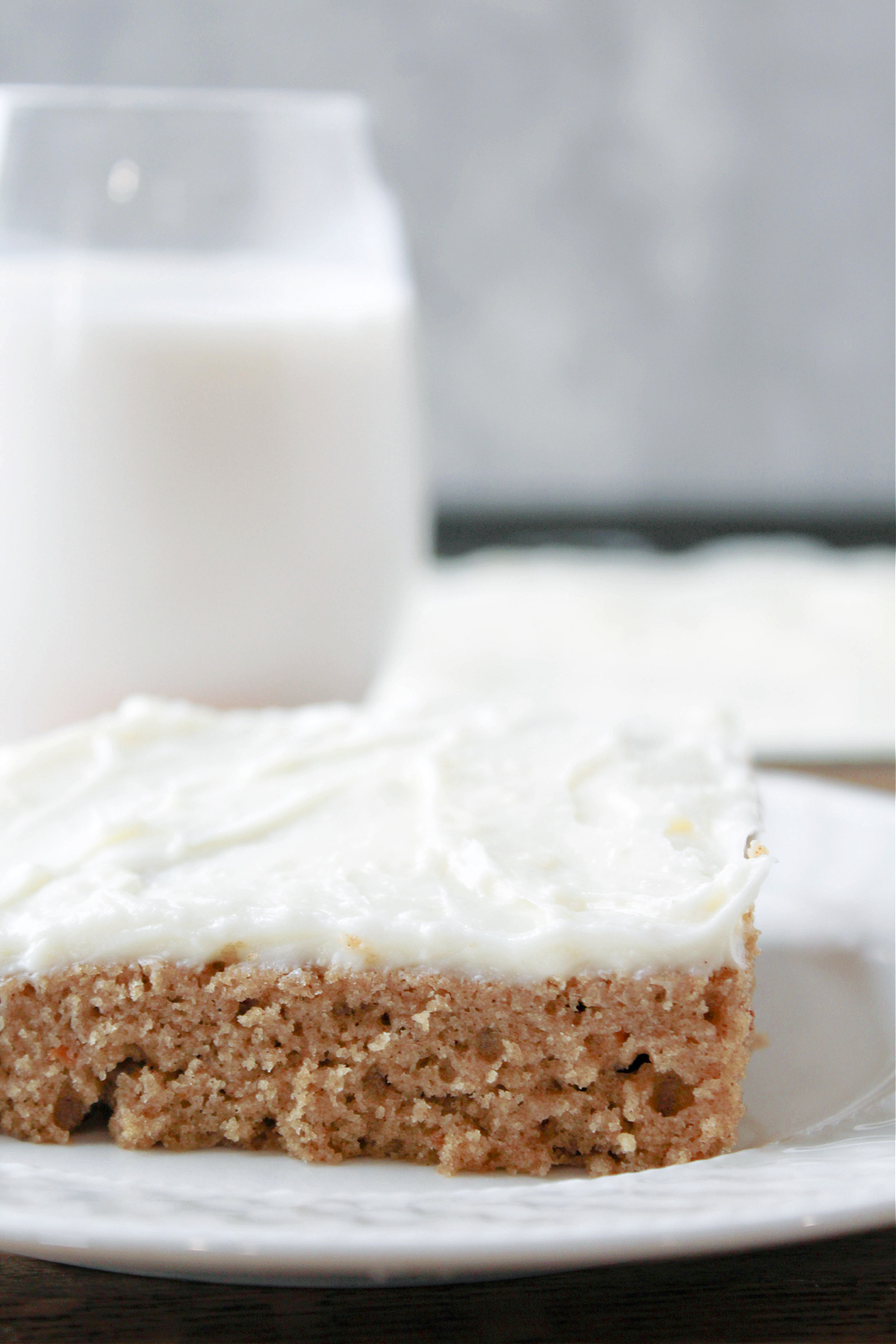 carrot cake on a white plate with milk behind. 