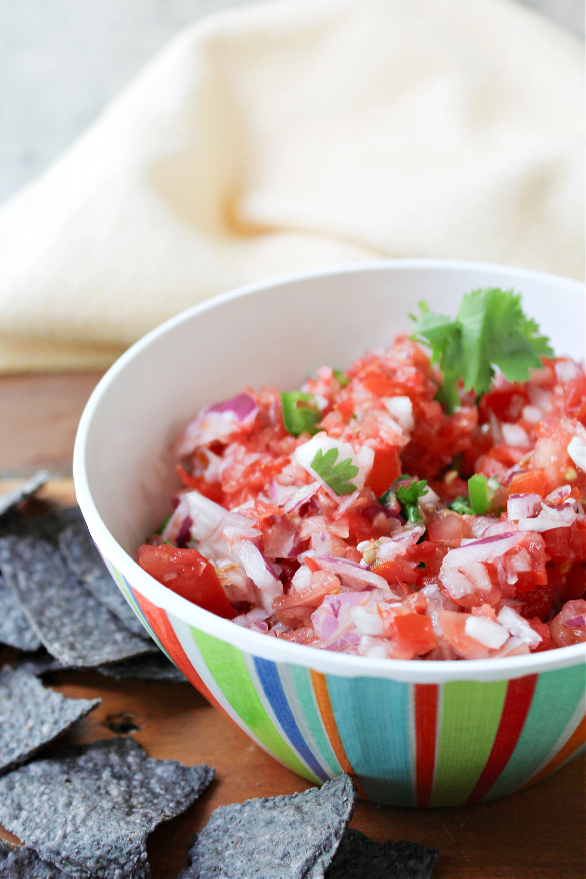 pico de gallo in a colored bowl with chips besides.