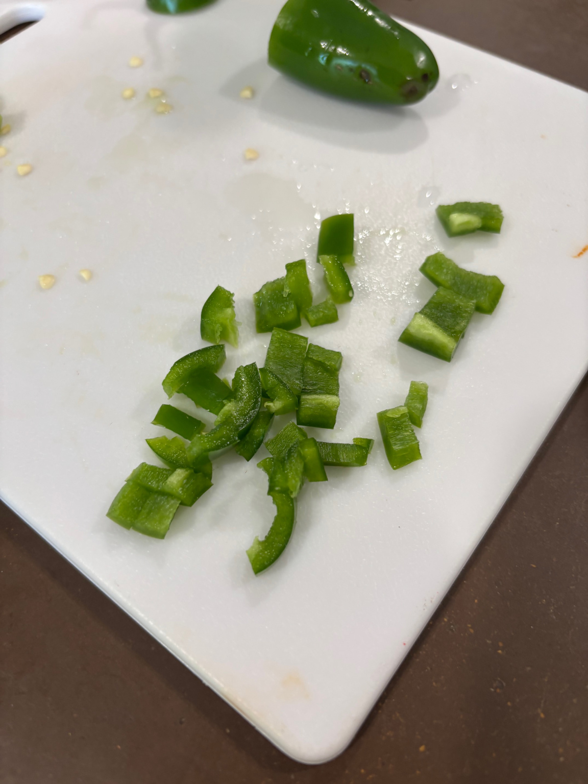chopped jalapeno peppers on a white cutting board. 