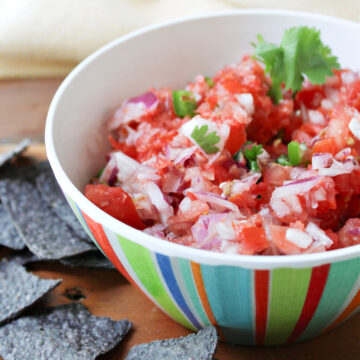 Pico de Gallo in a colored bowl the blue chips besides.