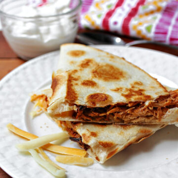 BBQ quesadilla on a white plate with cheese.