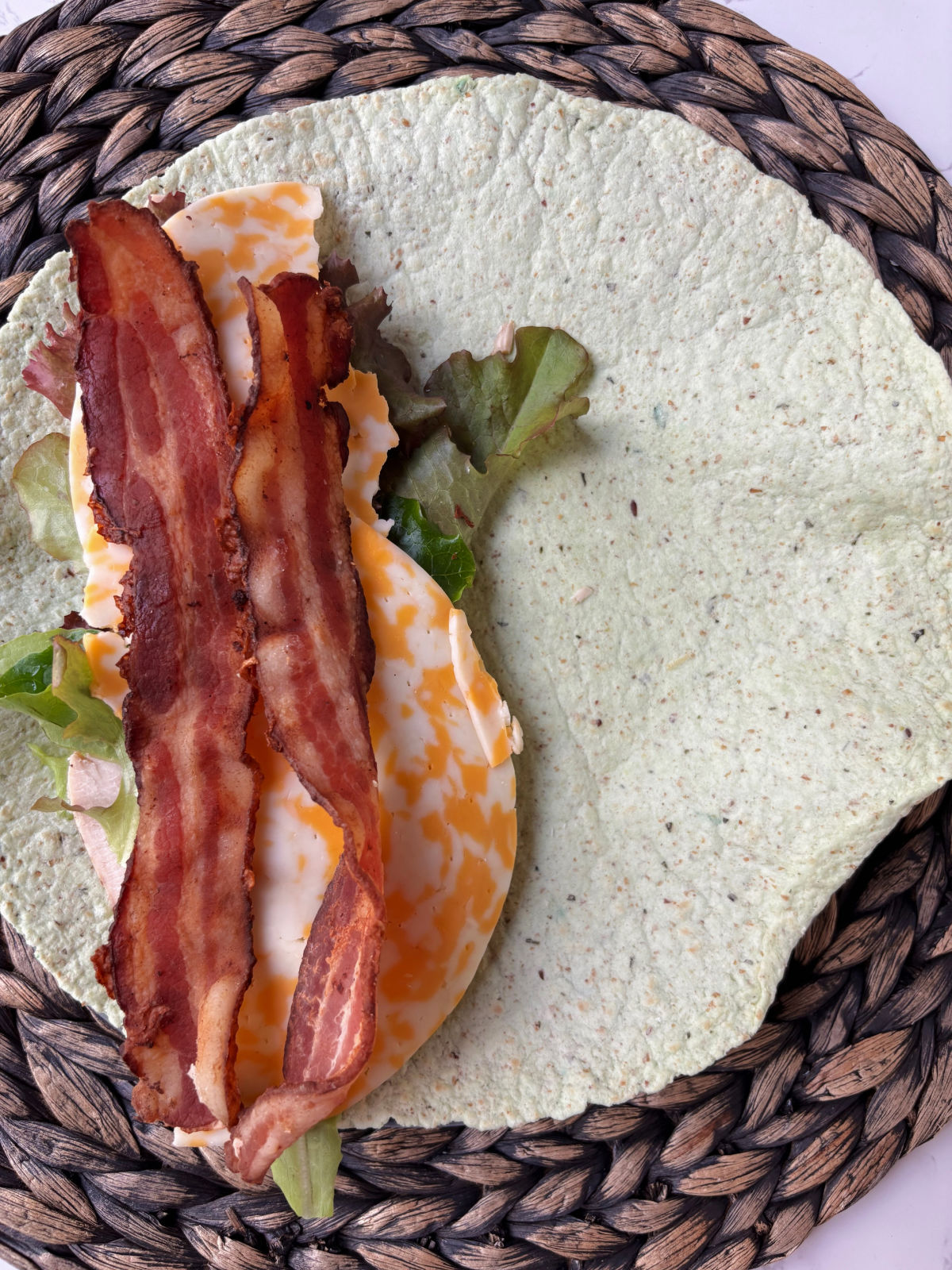 bacon on top of chicken, lettuce and cheese.