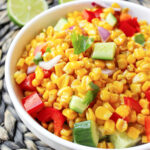 corn salad with vegetables in a white bowl.