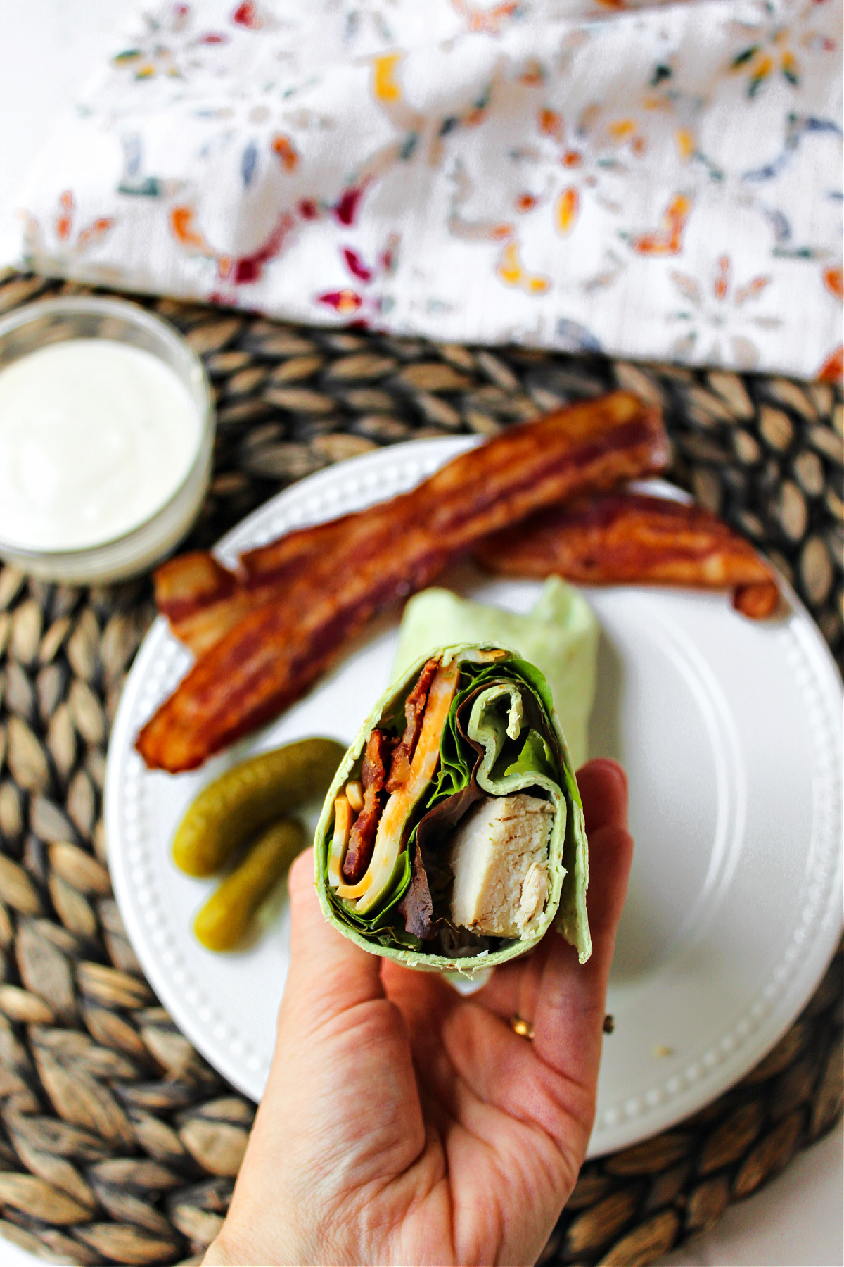 inside of a grilled chicken wrap with bacon on a plate.