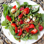 spinach strawberry salad on a white plate.
