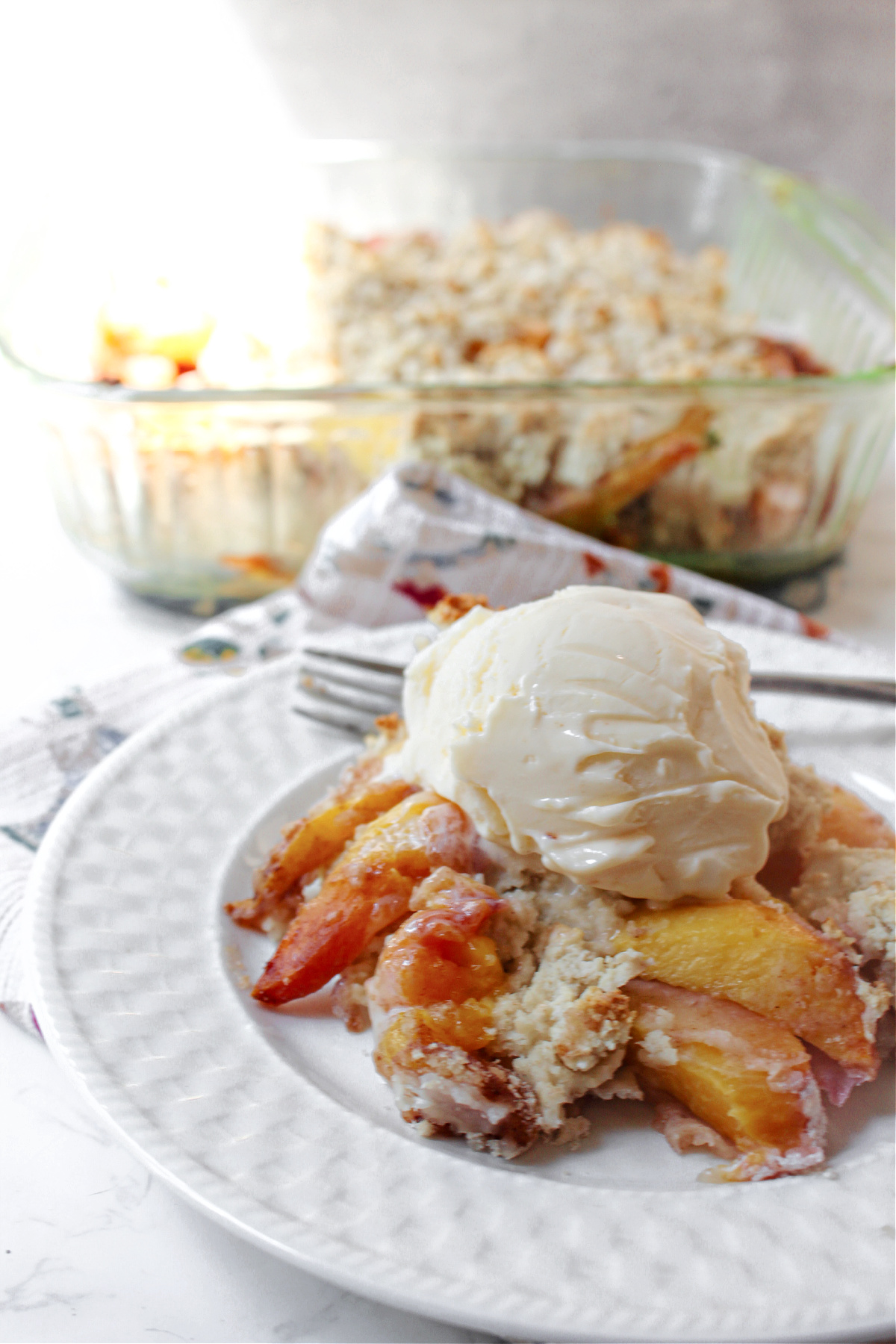 peach cobbler on a white plate with a fork.
