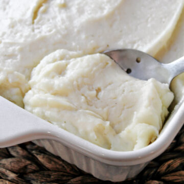 party potatoes in a white baking dish with a spoon.