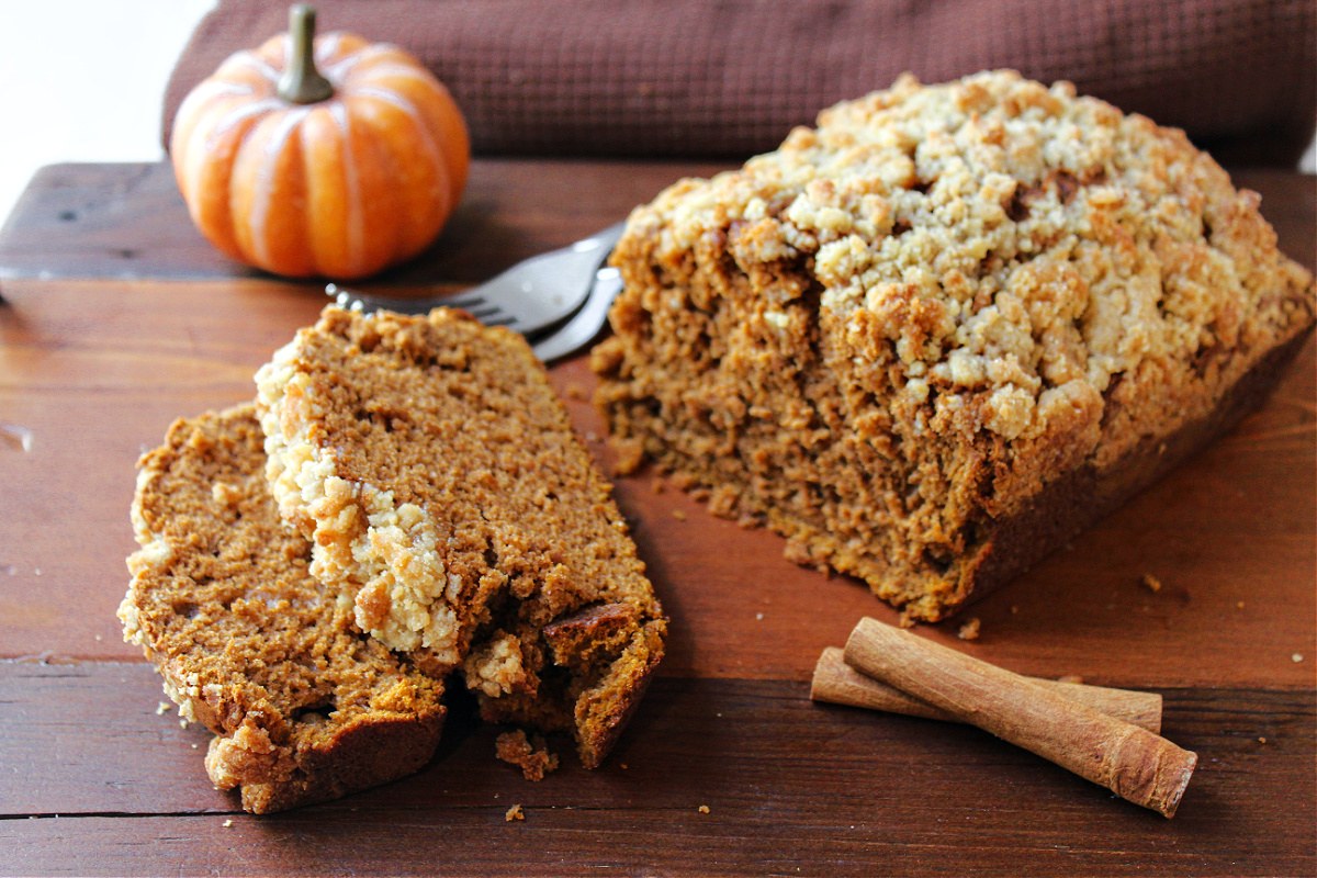 pumpkin coffee cake with a pumpkin behind and cinnamon sticks.