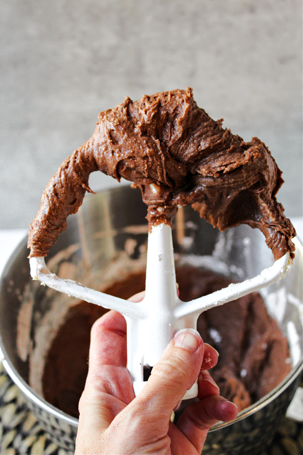 chocolate frosting with a hand holding a mixer paddle.