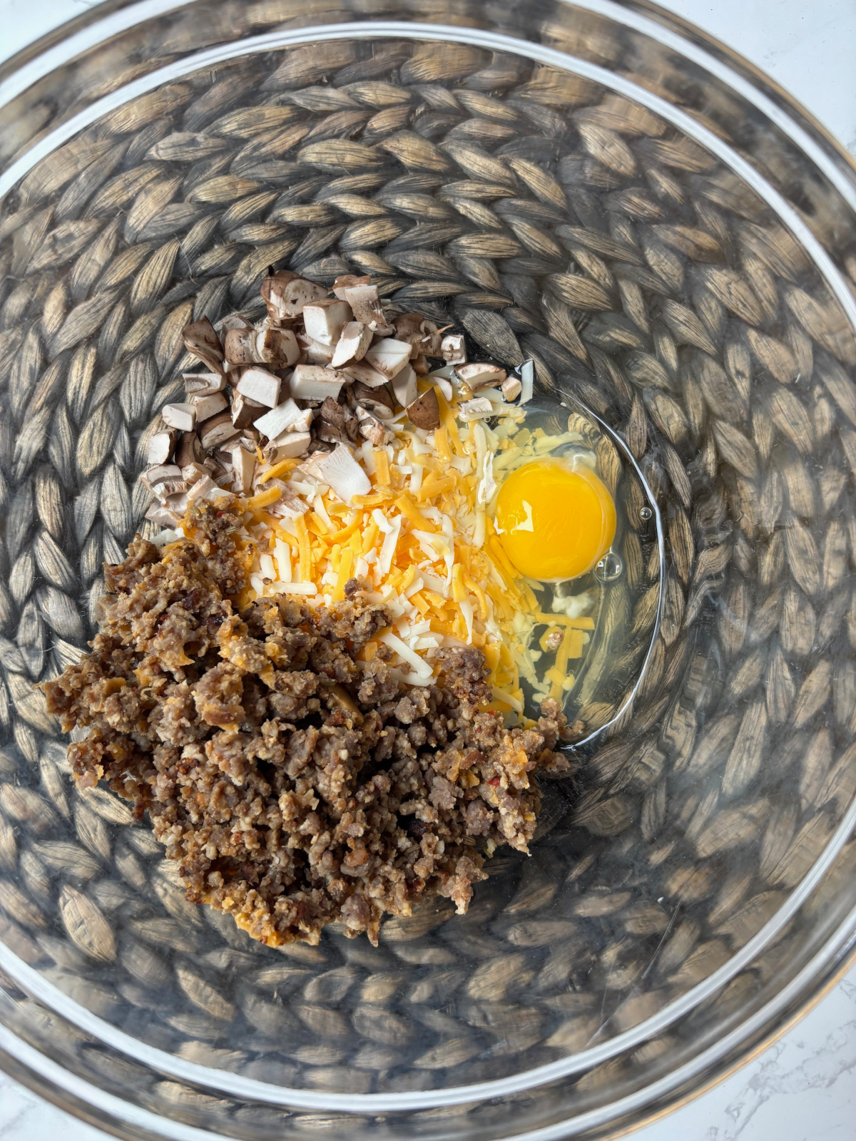 sausage and egg with cheese in a clear bowl.