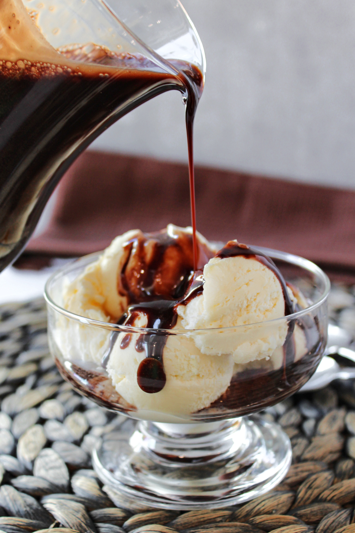 chocolate sauce being poured on ice cream.