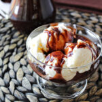ice cream in a clear bowl with homemade chocolate sauce on top.