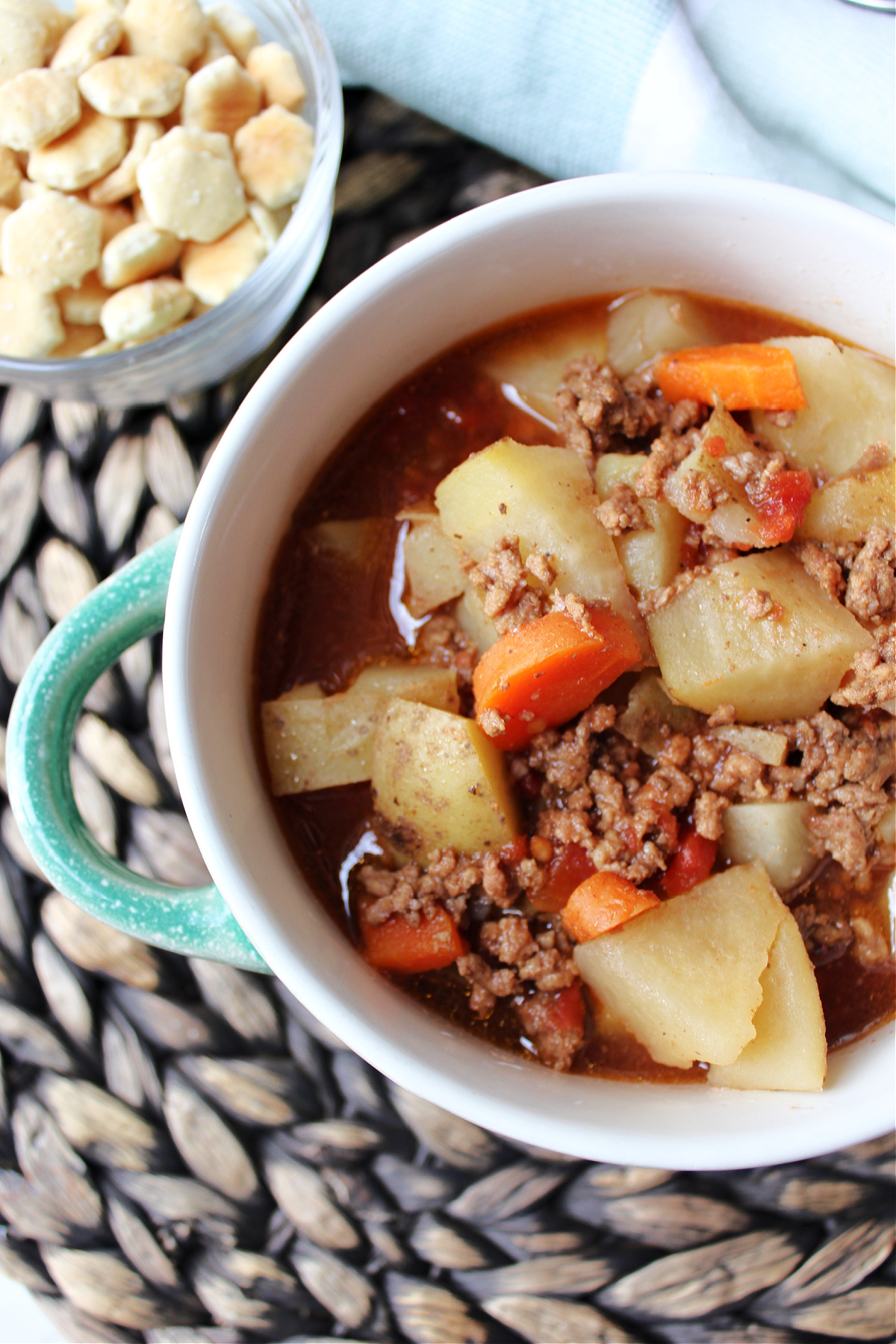 a soup with potatoes, hamburger, carrots in a beef broth in a bowl. 