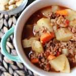 soup in a green bowl with crackers besides.