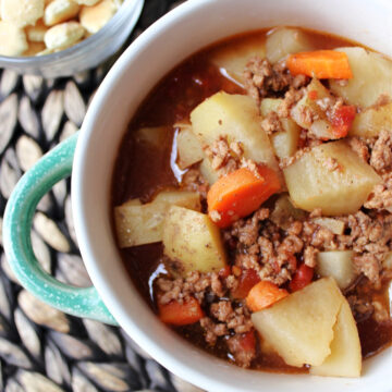 soup in a green bowl with crackers besides.