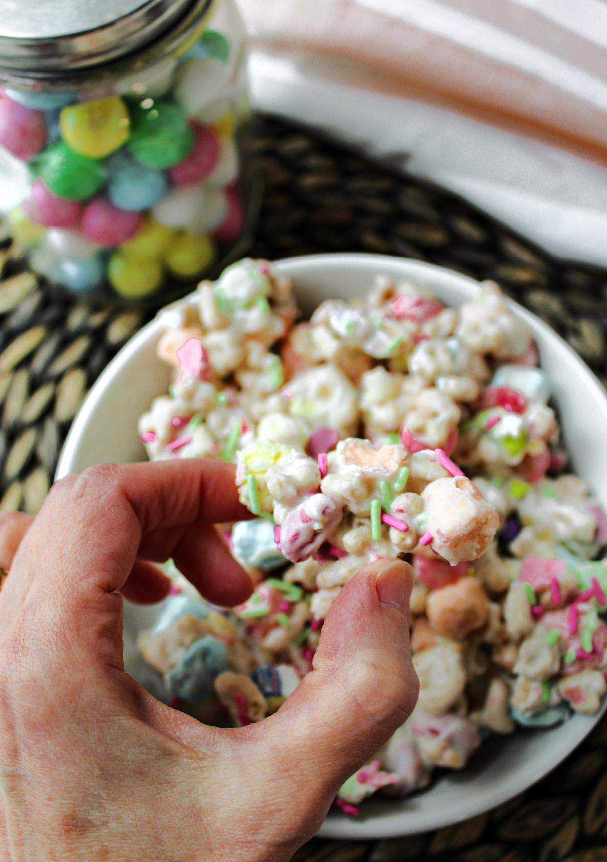 Easter marshmallow candy in a white bowl with a hand holding it.