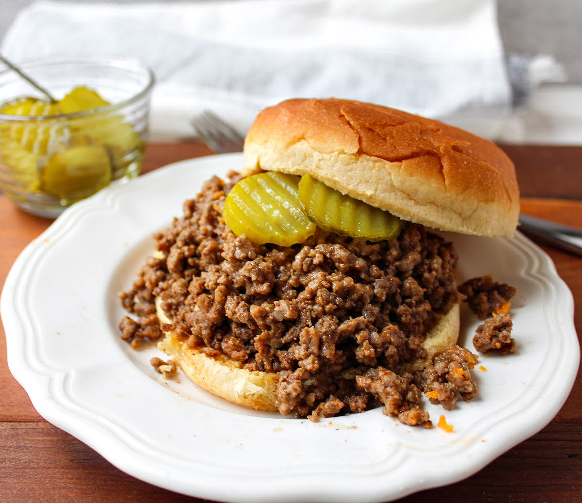 cheeseburger bbq on a white plate with pickles. 