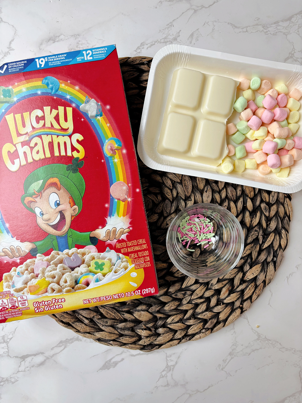 Lucky Charms box with marshmallows, almond bark and sprinkles.