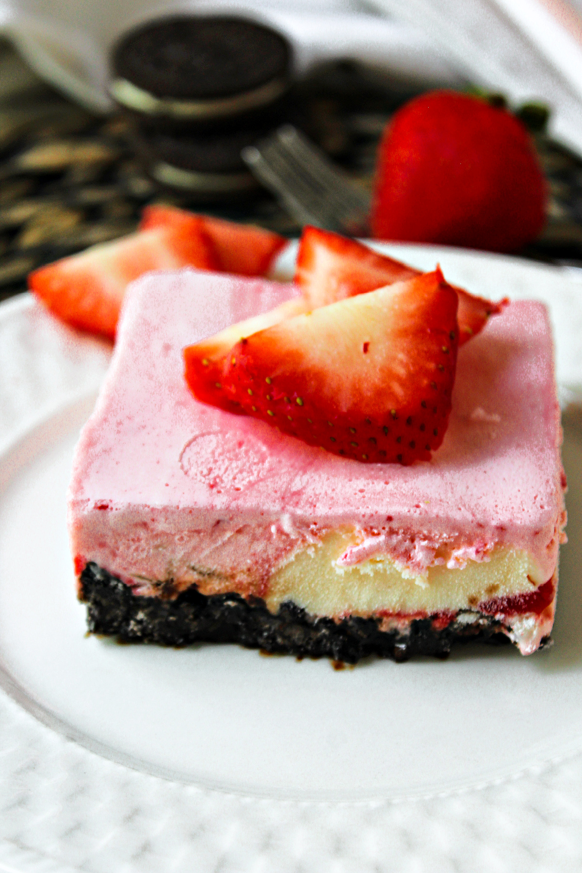 strawberry cheesecake ice cream with strawberries on top on a white plate.