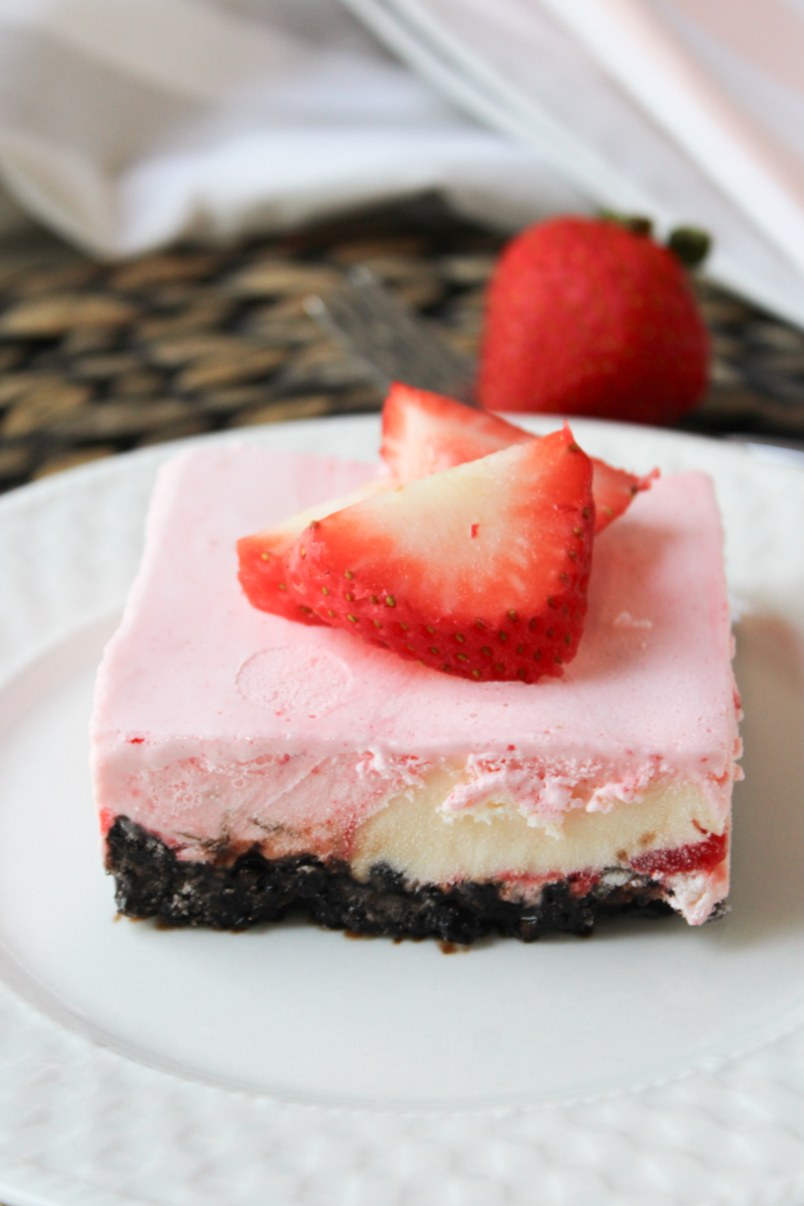 a piece of strawberry cheesecake ice cream dessert on a white plate. 