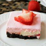 strawberry cheesecake ice cream dessert on a white plate with strawberries on top.