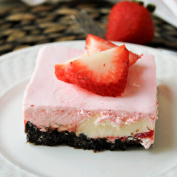 strawberry cheesecake ice cream dessert on a white plate with strawberries on top.