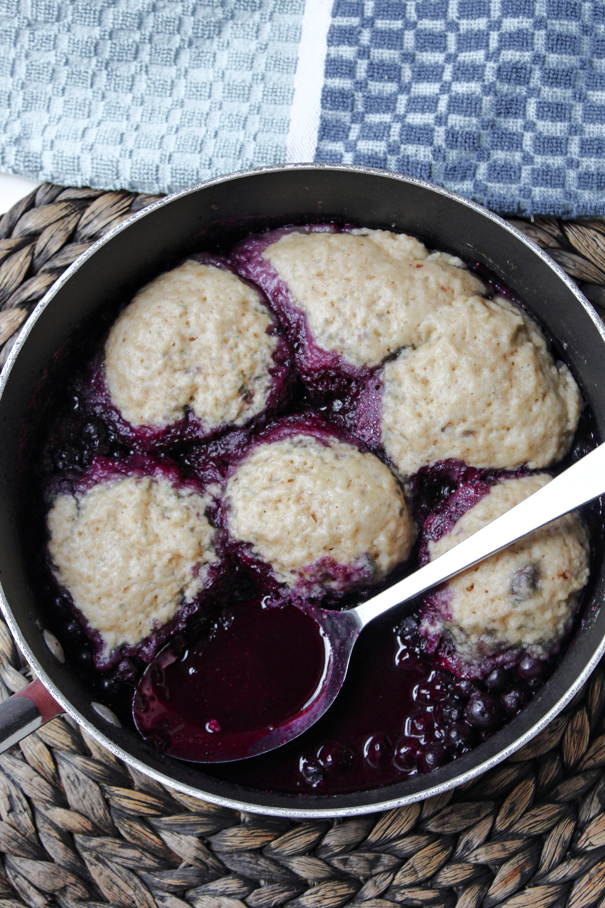 blueberry dumplings in a pan with a spoon.