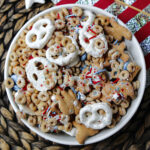 Patriotic party mix in a white bowl with pretzels, Cheerios, M&M's and animal crackers.