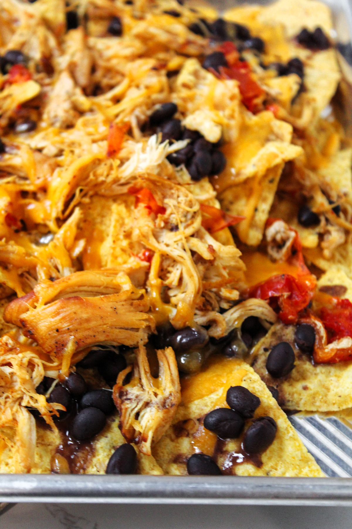chips, beans and chicken on a sheet pan with cheese on top. 