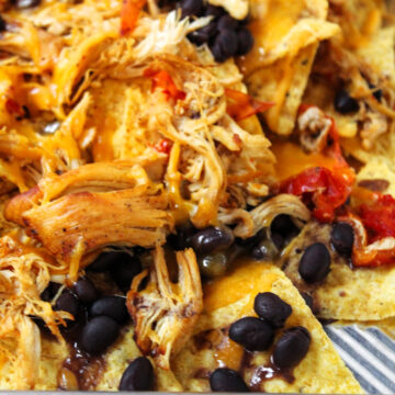 tortilla chips, chicken, peppers and beans on a sheet pan.