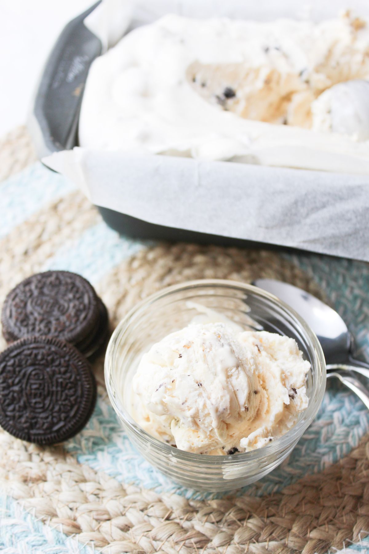 no churn oreo ice cream in a small clear bowl with a spoon besides. 
