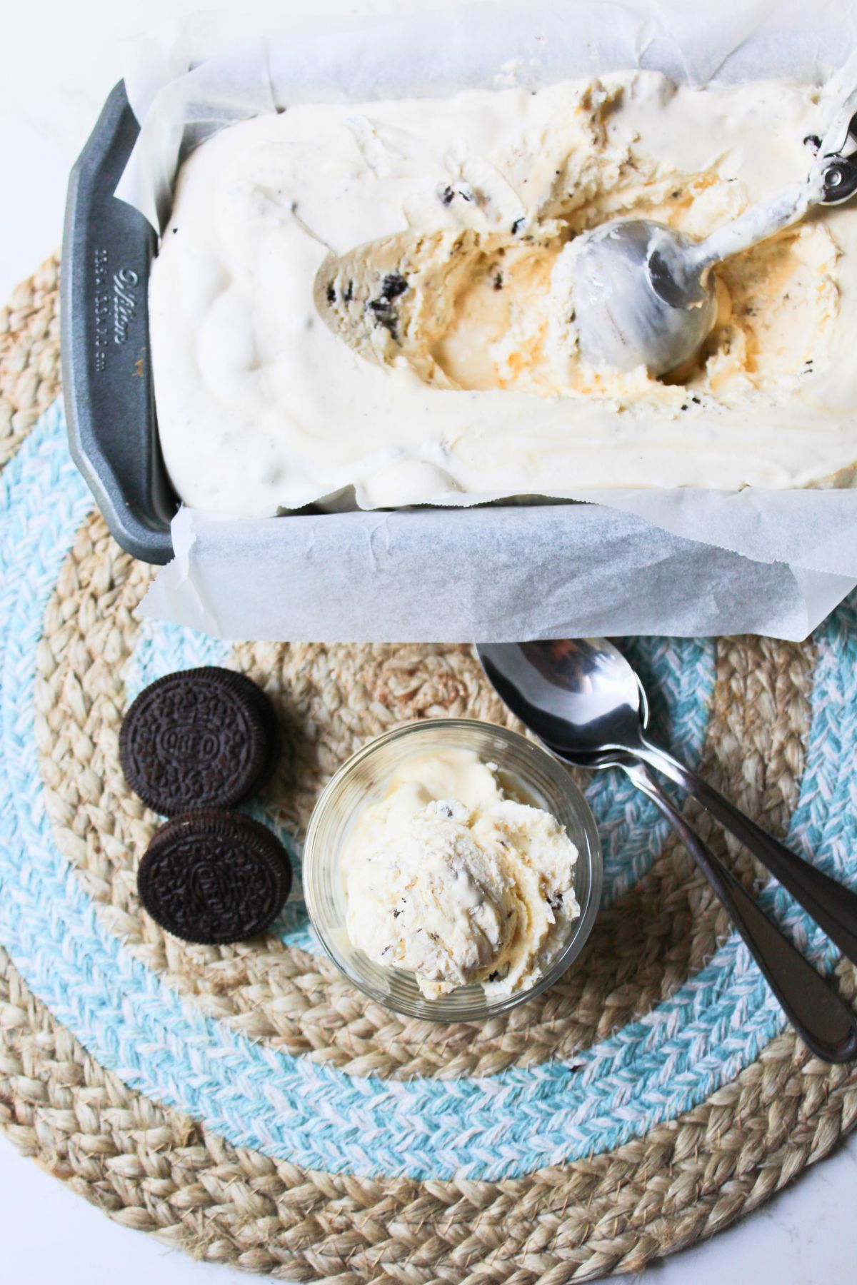 no churn ice cream in a dish on a mat with Oreos and spoons.